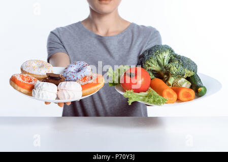 Cropped shot of woman holding plaques avec des bonbons et des légumes Banque D'Images