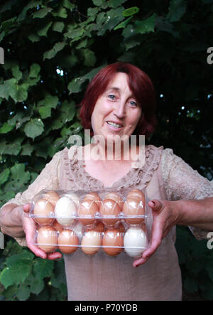 Smiling woman holding oeufs dans un pack en plastique,image Banque D'Images