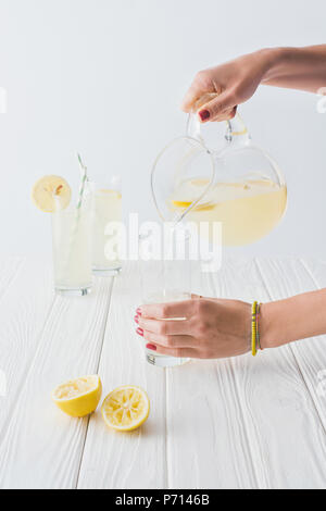 Cropped shot of woman pouring lemonade dans un verre sur fond gris Banque D'Images