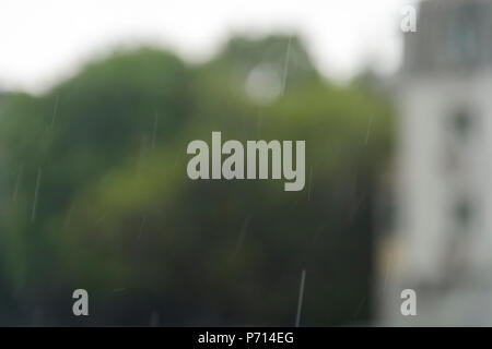 La forte pluie, gouttes vertical contre maisons floues en arrière-plan Banque D'Images