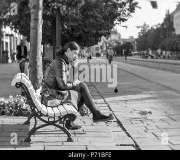 KOSICE, SLOVAQUIE - Octobre 2, 2017 : belle jeune femme assise avec le smartphone sur le banc dans la vieille ville en noir et blanc. Plus grande ville dans l'est sl Banque D'Images