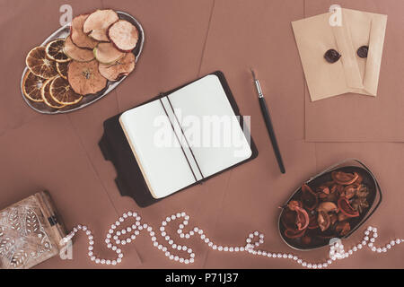 Vue de dessus de l'ordinateur portable, boîte de bijoux, les fruits secs et les enveloppes sur fond de papier brun Banque D'Images