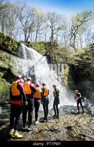 Un instructeur supervise un groupe de marche de l'aventure gorge avec le pays de Galles sur la rivière près de Mellte Pontneddfechan dans les Brecon Beacons UK Banque D'Images