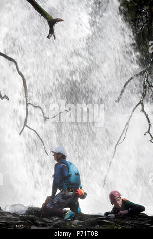 Un instructeur supervise un groupe de marche de l'aventure gorge avec le pays de Galles sur la rivière près de Mellte Pontneddfechan dans les Brecon Beacons UK Banque D'Images