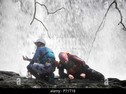 Un instructeur supervise un groupe de marche de l'aventure gorge avec le pays de Galles sur la rivière près de Mellte Pontneddfechan dans les Brecon Beacons UK Banque D'Images