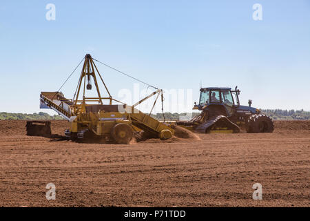 Tracteur agricole avec l'ensileuse du stockage de tourbe fraisée lâche (récolte) suivi par Miller à la tourbière prospère dans le comté de Kildare, Irlande. Banque D'Images