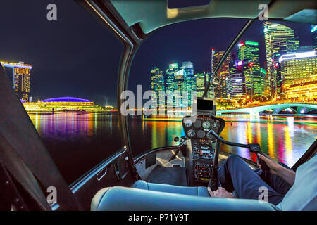 Cabine de l'hélicoptère en vol d'intérieur sur Panorama de Singapour les bâtiments et gratte-ciel du centre-ville reflète dans la mer. Singapour vol panoramique de nuit. Scène de nuit bord de mer de Marina Bay. Banque D'Images