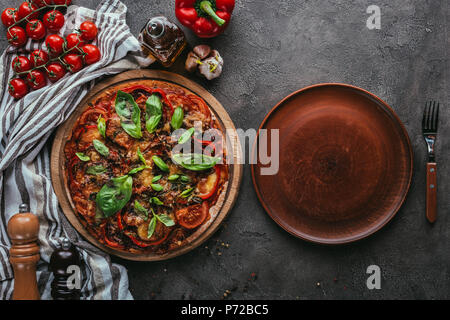 Vue de dessus de délicieuse pizza avec plaque rustique sur table béton Banque D'Images