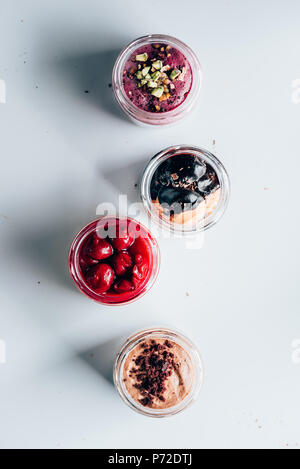 Vue de dessus de différents mets sucrés savoureux desserts dans des bocaux en verre sur blanc Banque D'Images