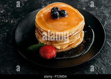 Pile de crêpes aux fruits rouges fraîchement appuyé sur le tableau noir Banque D'Images