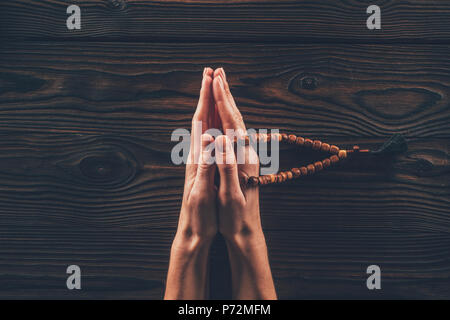 Portrait of woman holding rosary et priant à table Banque D'Images