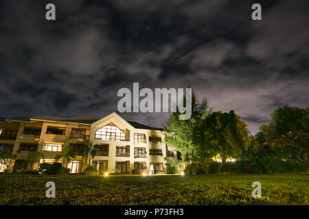 Niveau du sol grand angle shot d'un hotel à l'Ile Maurice dans la nuit avec des nuages en mouvement, lumières, arbres, pelouse Banque D'Images