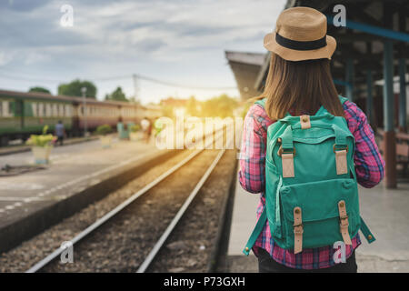 Traveler femme marche et attend le train sur un quai de gare, la lumière du soleil l'arrondi, Selective focus Banque D'Images
