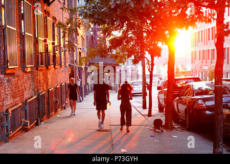 Les gens qui marchent dans la rue alors que le soleil se couche à Williamsburg, Brooklyn, New York, NY Banque D'Images