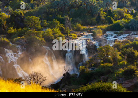 Epupa Falls sur la rivière Kunene au nord de la Namibie et du sud de l'Angola frontière. Lever du soleil la lumière du soleil dans l'eau de la brume. Banque D'Images