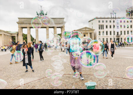 Bulles de savon coloré flottant dans l'avant-plan. Artiste de rue, musicien ambulant, divertissant la foule devant la porte de Brandebourg à Berlin. Banque D'Images