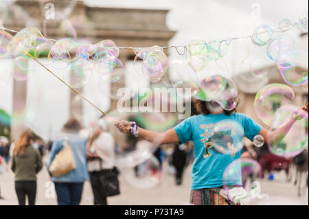 Bulles de savon coloré flottant dans l'avant-plan. Artiste de rue, musicien ambulant, divertissant la foule devant la porte de Brandebourg à Berlin. Banque D'Images