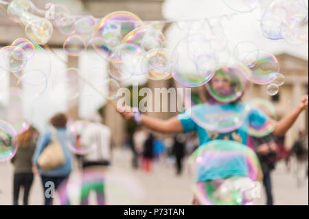 Bulles de savon coloré flottant dans l'avant-plan. Artiste de rue, musicien ambulant, divertissant la foule devant la porte de Brandebourg à Berlin. Banque D'Images