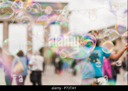 Bulles de savon coloré flottant dans l'avant-plan. Artiste de rue, musicien ambulant, divertissant la foule devant la porte de Brandebourg à Berlin. Banque D'Images