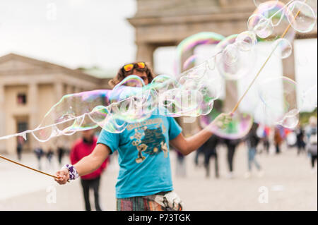 Bulles de savon coloré flottant dans l'avant-plan. Artiste de rue, musicien ambulant, divertissant la foule devant la porte de Brandebourg à Berlin. Banque D'Images