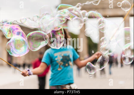 Bulles de savon coloré flottant dans l'avant-plan. Artiste de rue, musicien ambulant, divertissant la foule devant la porte de Brandebourg à Berlin. Banque D'Images