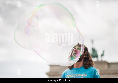 Bulles de savon coloré flottant dans l'avant-plan. Artiste de rue, musicien ambulant, divertissant la foule devant la porte de Brandebourg à Berlin. Banque D'Images