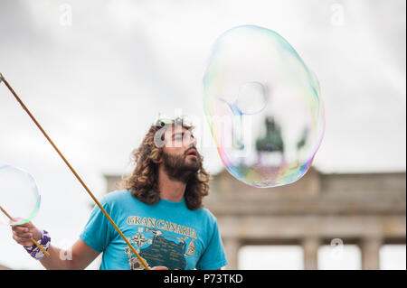 Bulles de savon coloré flottant dans l'avant-plan. Artiste de rue, musicien ambulant, divertissant la foule devant la porte de Brandebourg à Berlin. Banque D'Images