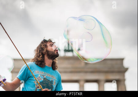 Bulles de savon coloré flottant dans l'avant-plan. Artiste de rue, musicien ambulant, divertissant la foule devant la porte de Brandebourg à Berlin. Banque D'Images