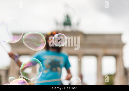 Bulles de savon coloré flottant dans l'avant-plan. Artiste de rue, musicien ambulant, divertissant la foule devant la porte de Brandebourg à Berlin. Banque D'Images