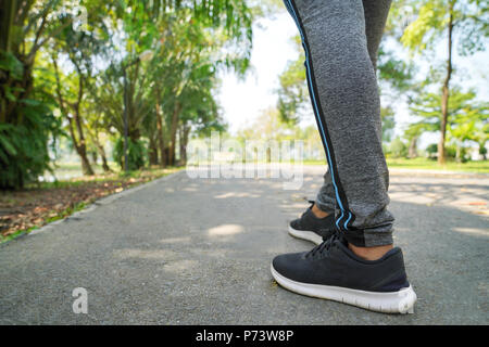 Arrière-plan de sports pieds Runner, s'exécutant sur gros plan sur la route, Chaussure femme Sport running sur route au lever du soleil, un centre de remise en forme et de bien-être d'entraînement concept. Banque D'Images