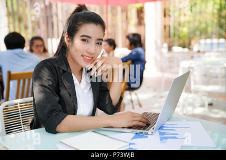 Portrait of smiling jolie jeune femme d'affaires dans les verres assis sur lieu de travail Banque D'Images