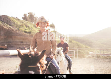 Joli couple amis jeunes ride beaux chevaux dans une école de plein air. sun rétroéclairage pour image lumineuse dans des lieux chaleureux. filtre wi Banque D'Images