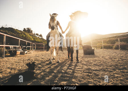 L'équitation de paysage avec deux personnes et animaux couple et un chien en tenant les mains avec de l'amour et l'amitié et le coucher de soleil en arrière-plan. w Banque D'Images