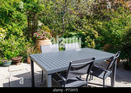 Terrasse fleurie avec mobilier de jardin gris dans un jardin au printemps Banque D'Images