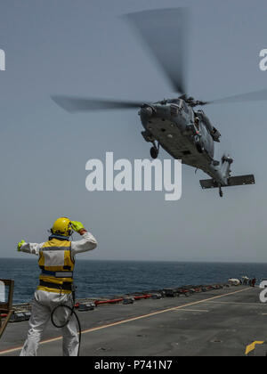 5e flotte ZONE DE RESPONSABILITÉ (15 mai 2013) Les navires l'Adjudant Steve Cooper des signaux à un SH-60 Sea Hawk affectés à l'Escadron d'hélicoptères de combat de la mer (HSC) 26 pendant les opérations de vol à bord de la Royal Fleet Auxiliary navire d'assaut amphibie de demandes La Baie de Cardigan (L3009) dans le cadre d'un transfert international de passagers au cours de l'exercice de lutte contre les mines (IMCMEX) 2013. IMCMEX 13 marines comprend de plus de 40 pays dont l'objectif est de promouvoir la sécurité régionale par les opérations de lutte contre les mines dans la 5e flotte des États-Unis zone de responsabilité. Banque D'Images