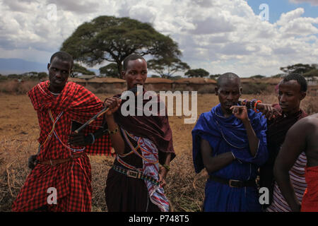 Pas de village près d'Amboselli park, Kenya - 02 avril, 2015 : quatre guerriers Massaïs inconnue aux couleurs traditionnelles en robes, photographié quand meeti Banque D'Images