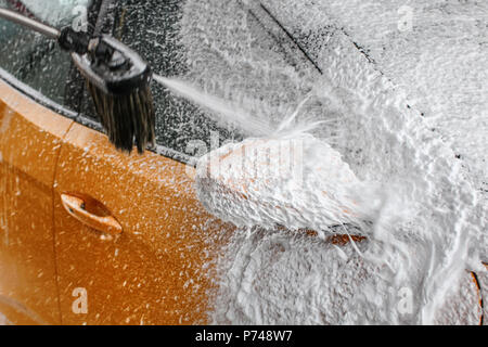 Détails sur voiture jaune rétroviseur latéral couvert de mousse épais shampooing blanc, plus d'arrosage, au lavage en lave-auto. Banque D'Images