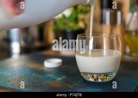 Verser la main le kéfir frais probiotik verre bouteilles en verre transparent, sur une table de cuisine. Banque D'Images