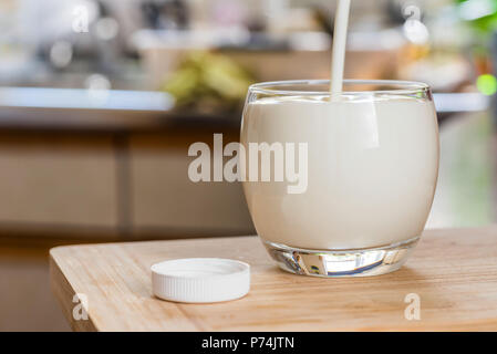 Verser la main le kéfir frais probiotik verre bouteilles en verre transparent, sur une table de cuisine. Banque D'Images