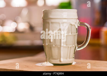 Vue rapprochée de kéfir frais probiotik verre au trop plein verre clair tasse sur une table de cuisine. Banque D'Images