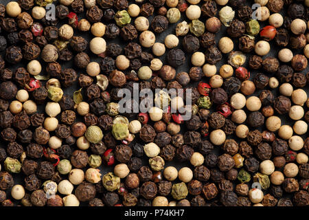 Extreme close up de mélange de poivre mélanger sur une pierre noire. Texture de fond alimentaire Macro Banque D'Images