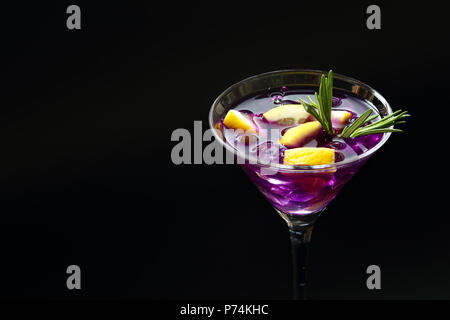 Close up d'un été frais Purple Rain cocktail dans un verre à cocktail avec de la glace, les tranches de citron et thym sur une surface texturée noire Banque D'Images