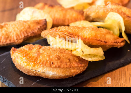 Empanadillas espagnols sur la plaque d'ardoise avec des frites Banque D'Images