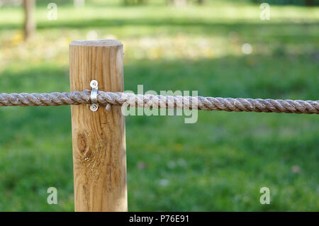 Pieu de bois avec des cordes d'épaisseur protège le pré vert. Soleil Vert pelouse Banque D'Images