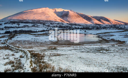 Blencathra dans la partie nord de la Lake District comme un soleil d'hiver se lève et se jette dans le Tarn Tewet réflexions Banque D'Images