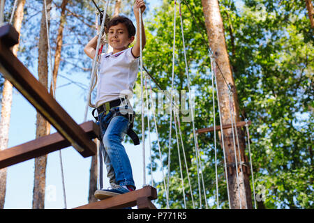 Cheerful preteen boy posing on swing au parc Banque D'Images