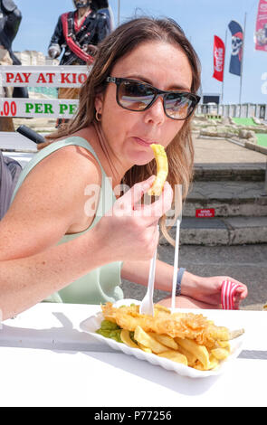 Young woman Eating fish and chips sur le front de mer de Brighton UK Banque D'Images