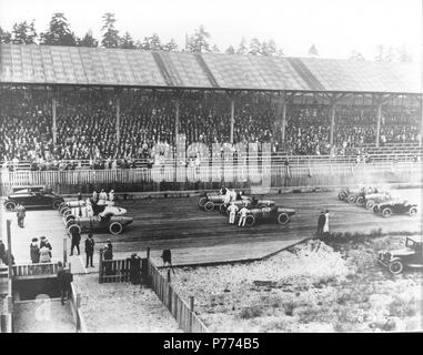 . Marvin D. Collection Boland BOLAND-B4370. Anglais : Vingt mille race fans entassés dans les gradins couverts de la Tacoma Speedway pour regarder le 4 juillet, 1921 Speedway Classic. Les pilotes, les mécaniciens et les officiels de la course sur la piste du conseil avant le début de la course de 250 milles. Les voitures de course sont alignés sur la piste trois au courant, avec la Speedster Marmon pace car dans le plomb. Dans la première rangée sont, de gauche à droite, # 6 Roscoe Sarles' Duesenberg, # 1 Eddie Hearne's Revere et spécial # 3 Frank Elliott Leach spécial. Rangée du milieu : # 5 Joe Thomas Duesenberg, # 7 Eddie Miller, la voiture n°2 pour Banque D'Images