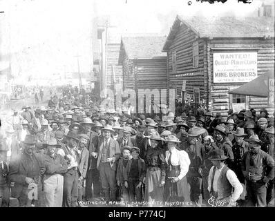 . Anglais : hommes et femmes en attente de courrier au bureau de poste, Dawson, Territoire du Yukon, ca. 1899. Anglais : Légende sur l'image : 'En attente de mail à Dawson City Bureau de poste' Émissions publicité pour A.J. Christian et compagnie, les courtiers de la mine. Sujets (LCTGM) : bureaux de poste--Yukon--Dawson ; constructions--Yukon--Dawson ; la publicité--Yukon--Dawson ; rues--Yukon--Dawson . vers 1899 8 hommes et femmes en attente de courrier au bureau de poste, Dawson, Territoire du Yukon, ca 1899 (HEGG 68) Banque D'Images