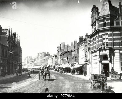 Anglais : Broad Street, Reading, à l'ouest de l'angle de la rue transversale, ch. 1891. Il y a un certain nombre de chariots et wagons dans la rue. Sur le côté nord, nos 54, 55 et 56 (A. H. Bull, draper) ; No 50 (William McIlroy, Boot and Shoe Warehouse) ; No 38 (Ebenezer Hill, marchand de cuir) ; No 28 (John Maud, horloger, bijoutier et opticien) ; Nos 24 et 25 de la capitale et des comtés (Banque mondiale). 1890-1899 : photographie par H. W. narguer ; verre négatif, n° 8135 Case 22. 1891 12 Broad Street, Reading, à l'ouest de l'angle de la rue transversale, ch. 1891 Banque D'Images